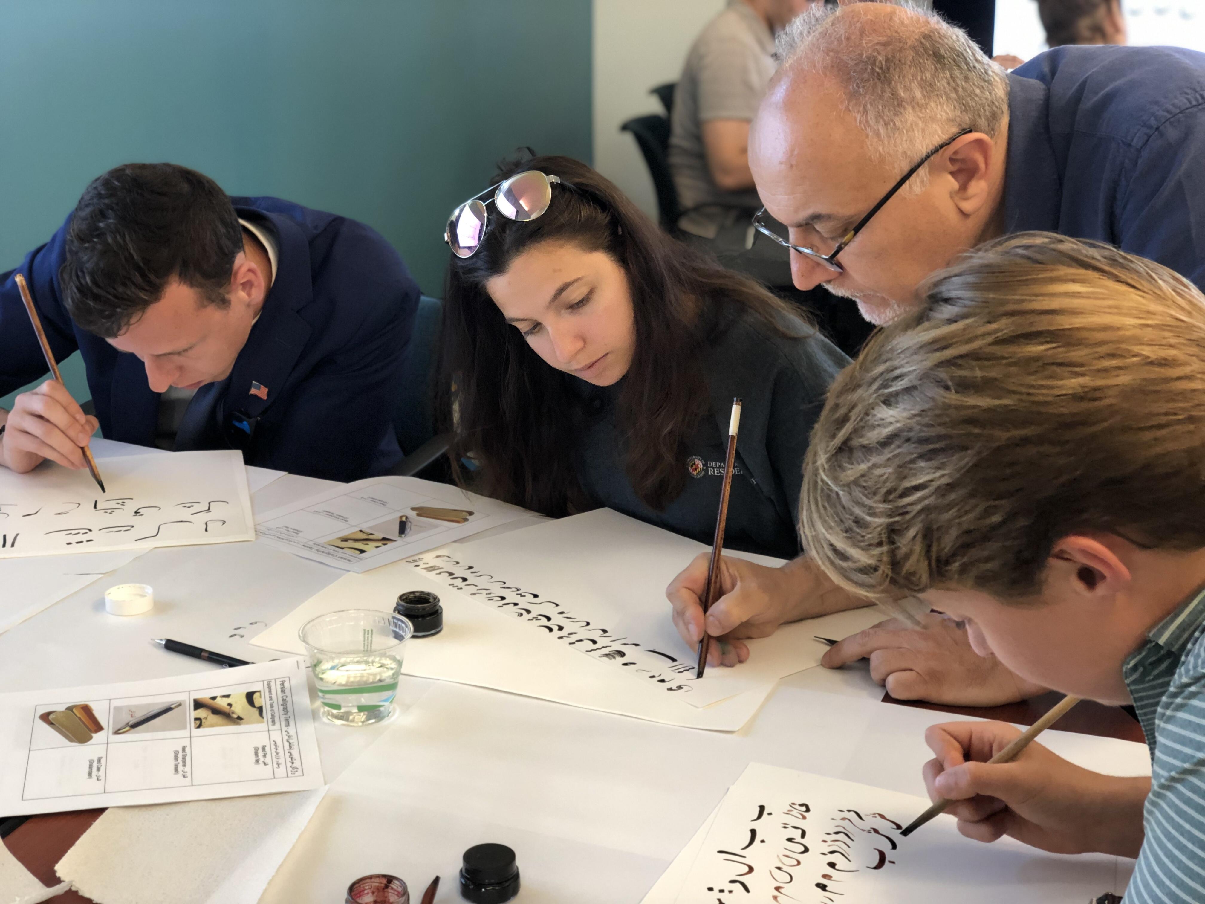 a professor works with students on their calligraphy