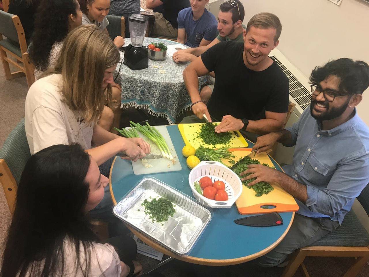 a group of students preparing a meal together and laughing