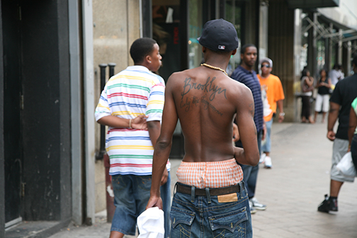 image still of man walking down a city street with his back towards the camera, jeans slouched and checkered boxer shorts showing