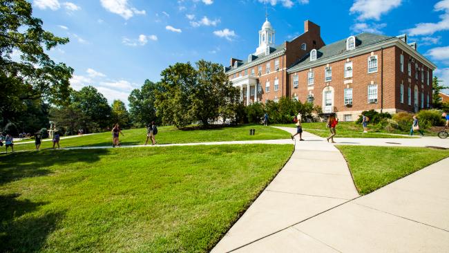 A shot of HJ Patterson Hall with students passing in front of it on sidewalk